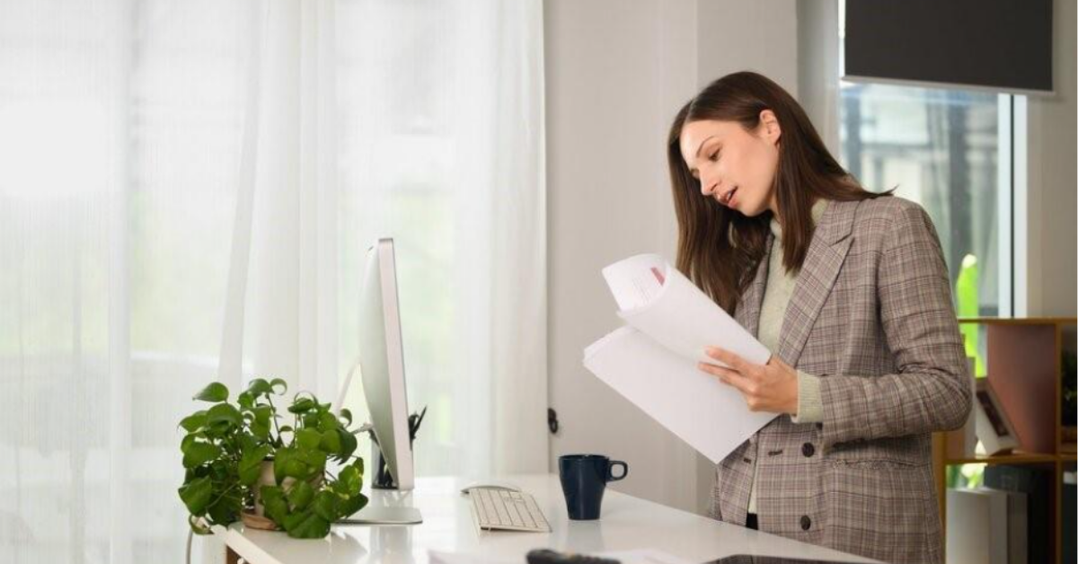 Professional female investor standing at her desk reviewing investment documents — representing the due diligence process accredited investors undertake when evaluating a real estate syndication sponsor