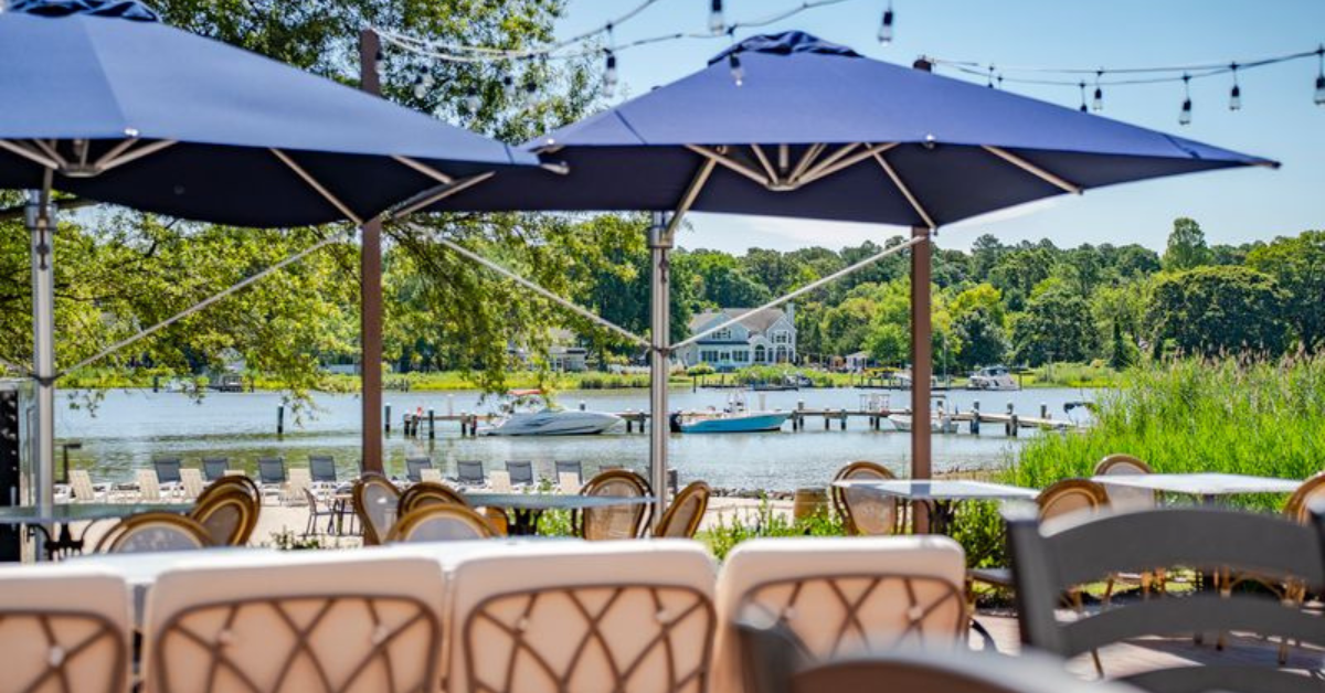kent-island-resort-waterfront-patio-dining-thompson-creek.jpg Waterfront patio dining at Kent Island Resort overlooking Thompson Creek and the marina dock, with boats moored at the resort's private dock