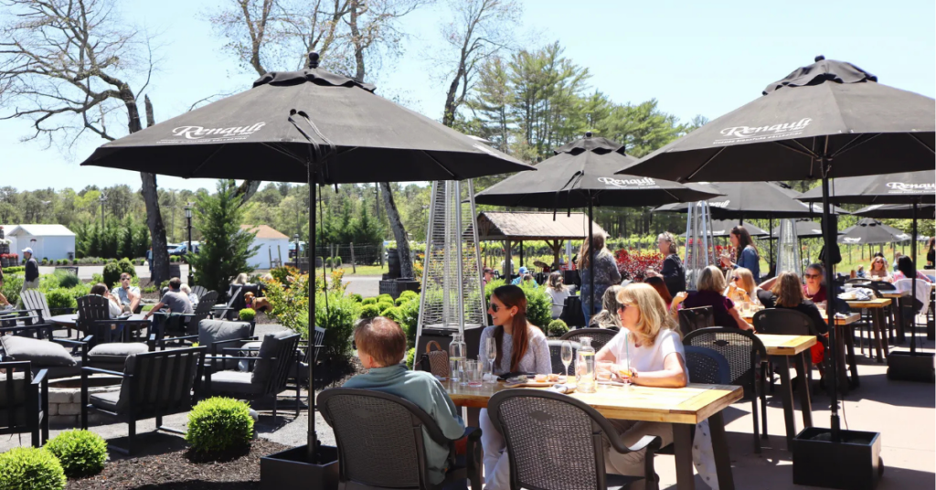 Outdoor_dining_Renault_Winery_Resort.jpg Guests dining outdoors at Renault Winery Resort under branded umbrellas with vineyard visible in background, illustrating multi-stream hospitality revenue at a destination resort