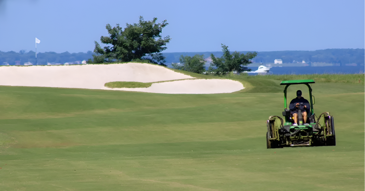 queenstown-harbor-golf-course-maintenance-waterfront.jpg Course maintenance equipment on the fairway at Queenstown Harbor Golf Resort with waterfront views, demonstrating the operational complexity that creates a barrier to entry in real asset investing.