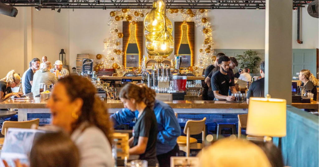 Taste_1864_at_Renault_Winery_Resort_people_enjoying_a_casual_afternoon.jpg Guests and staff at a busy food and beverage venue inside Renault Winery Resort, Egg Harbor City, New Jersey, showing active hospitality operations with bartenders serving a full house